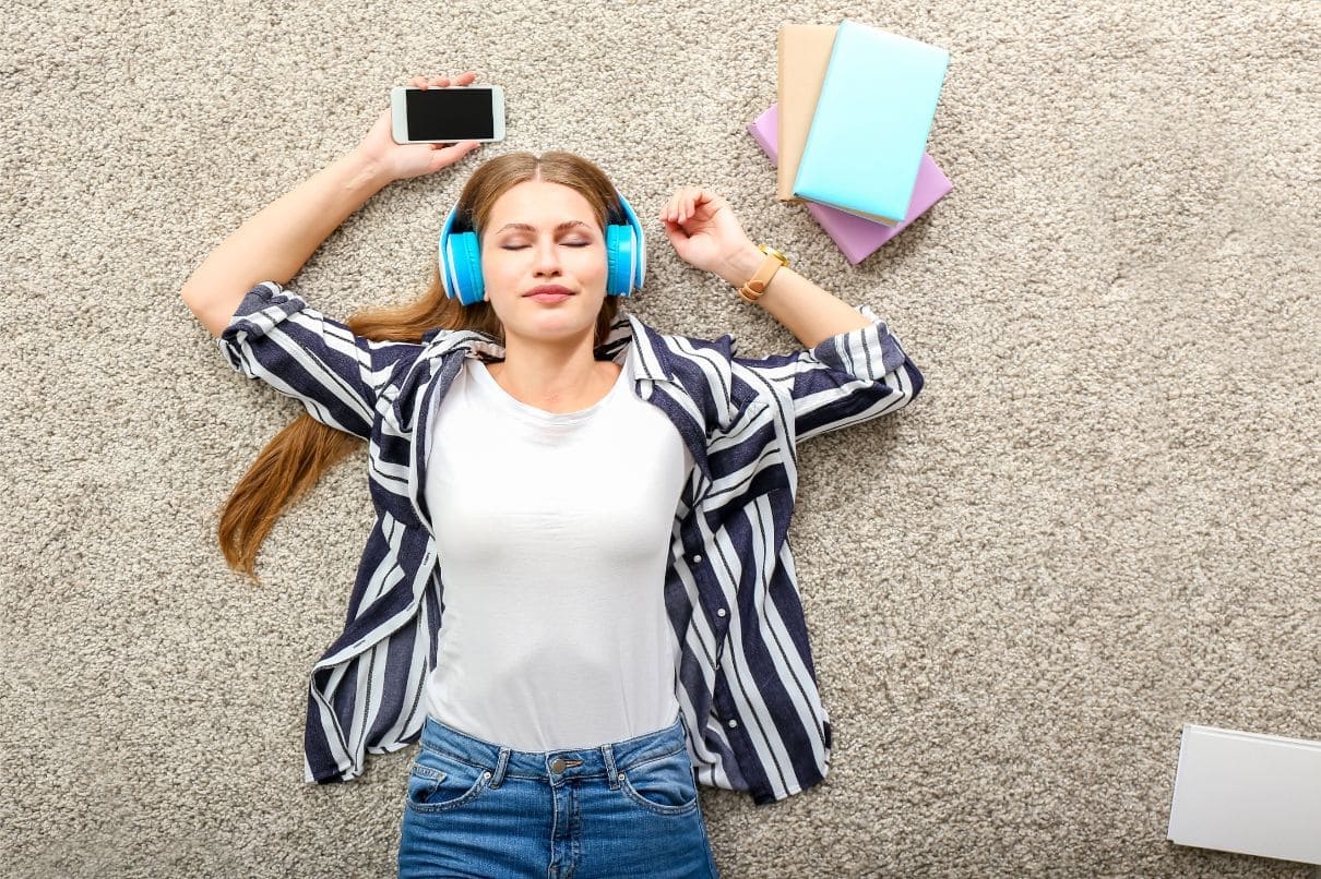 A woman lying on the floor, engrossed in a book, wearing headphones for an immersive experience.jpg